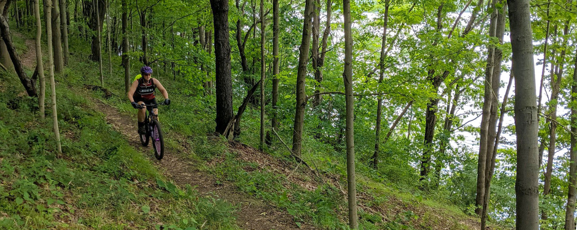 A woman rides a mountain bike on a wooded trail