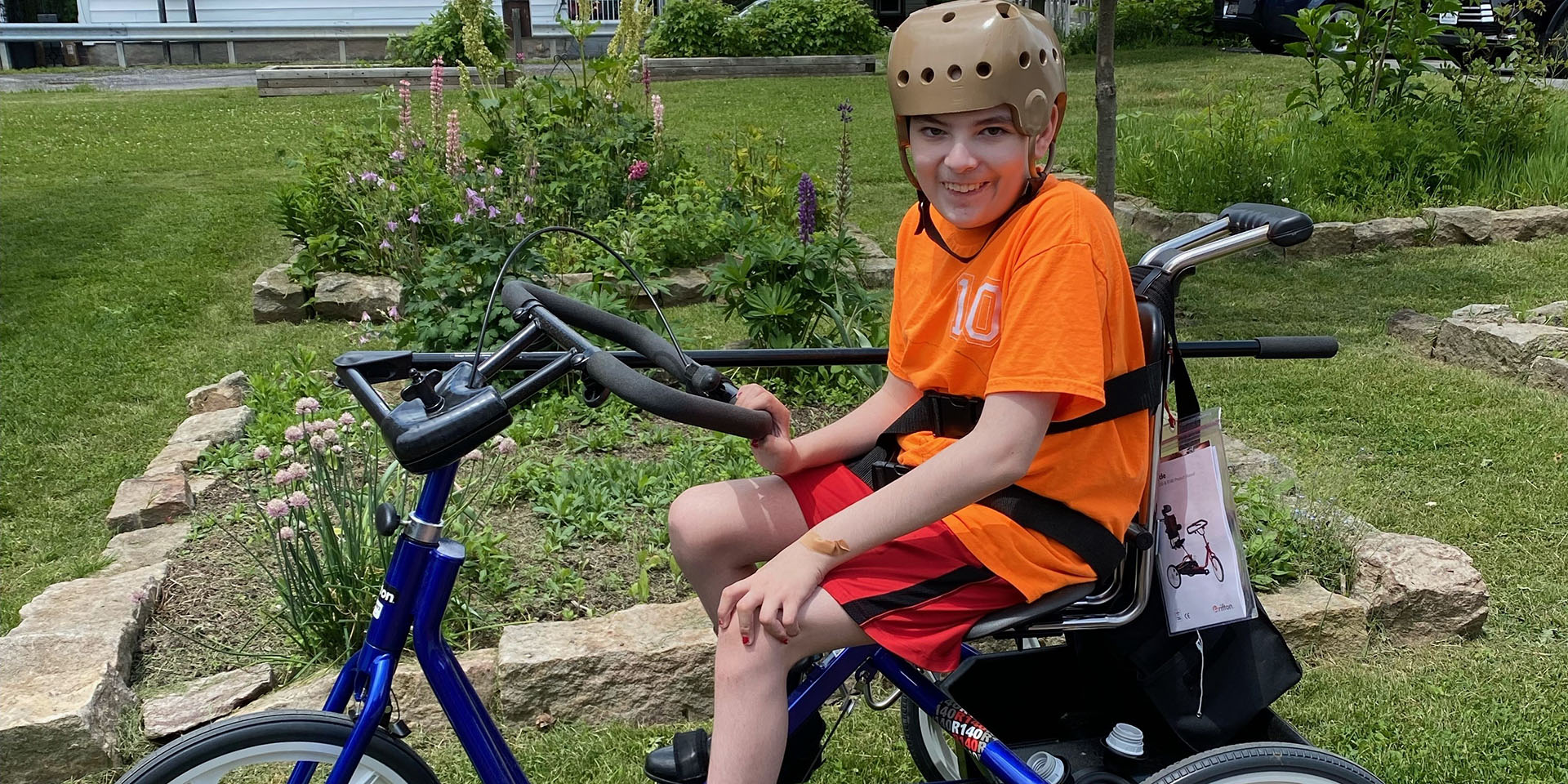 a happy boy sitting on an adaptive bicycle